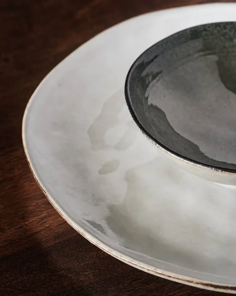 特写一张白色陶瓷盘的特写照片 上面有一个黑色的小碗 放在一张木制桌子上 — 图库照片