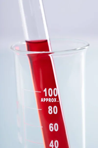 试管在烧杯内白色底座上装有红色液体的试管的特写镜头 — 图库照片
