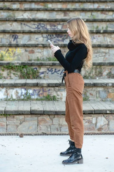 Una Joven Rubia Con Cuello Alto Negro Pantalones Beige Escribiendo — Foto de Stock