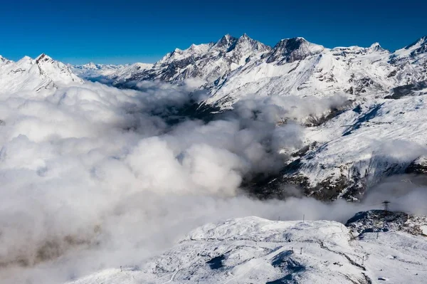 雪の息をのむような空中ショット 風光明媚な雲の下の山のキャップ — ストック写真