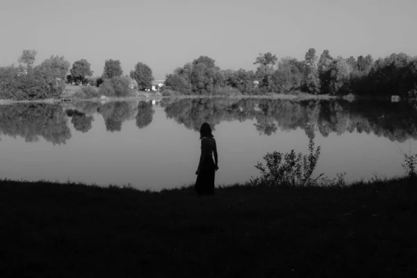 Šedivý Záběr Siluety Ženy Stojící Během Dne Jezera — Stock fotografie