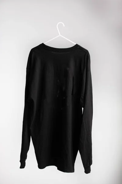 Ein Schwarzes Langarm Shirt Auf Kleiderbügel Mit Weißer Wand Hintergrund — Stockfoto