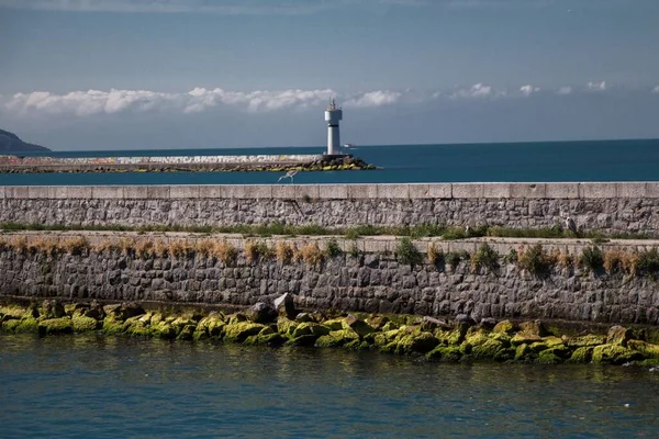 Een Oude Zeemuur Met Weinig Gras Een Vuurtoren Achtergrond Een — Stockfoto