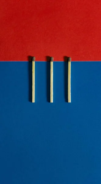 Вертикальний Знімок Трьох Сірників Синій Червоній Геометричній Поверхні — стокове фото