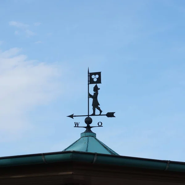 A weather vane on the roof on blue sky background