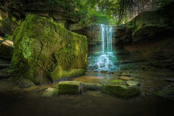 在长满青苔的岩石上的一个小瀑布的长期曝光镜头 — 图库照片