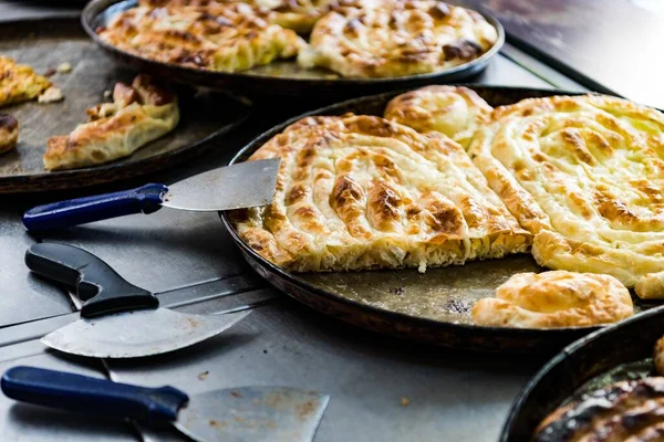 Ein Bosnischer Fleischkuchen Auf Einer Pfanne Mit Aufschnittmaschine Daneben — Stockfoto