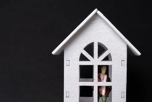 黒を背景に白いミニチュアの家の中の男の人形のおもちゃの閉鎖 — ストック写真