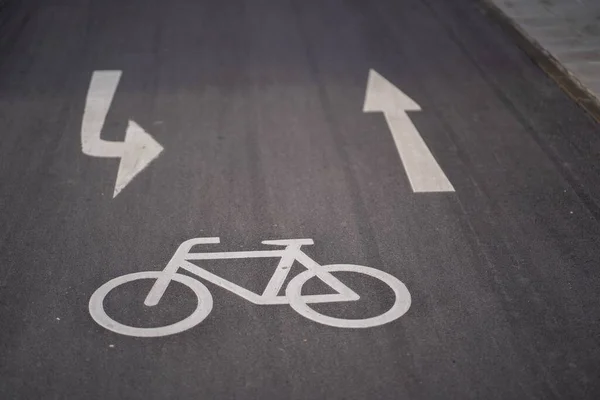 A high angle shot of a bicycle sign and two arrows on the asphalt ground