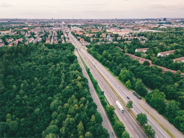 森林附近的高速公路的空中景观 许多汽车开到巴伐利亚的慕尼黑市 每天通勤 背景中的城市天际线 — 图库照片