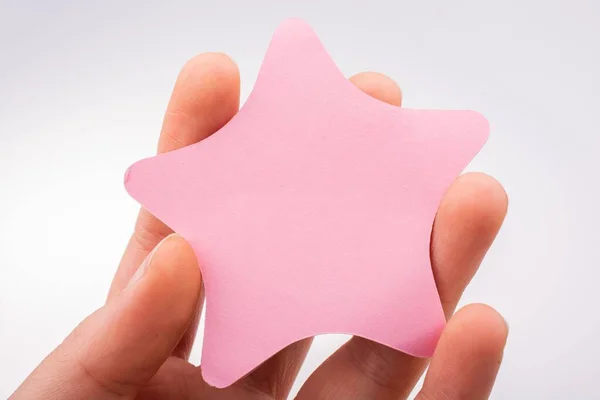 一只手拿着星形粉红的纸在白色的背景上 — 图库照片