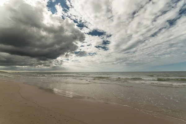 雲に覆われた空の下のビーチの海の波 — ストック写真