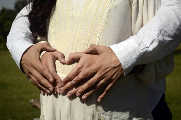 妊娠中の腹に手で心臓の形を作るカップル 赤ちゃん 家族の概念 — ストック写真