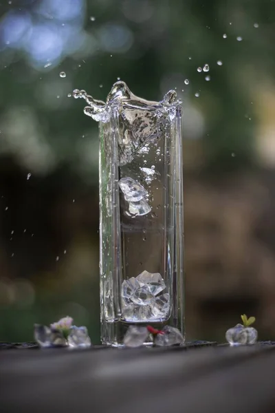 Ein Vertikales Bild Eis Das Ein Glas Fällt Und Wasserspritzer — Stockfoto