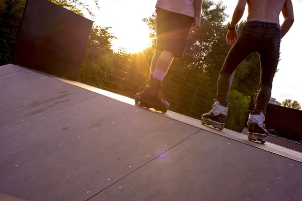 Két Fiatal Görkorcsolyázik Egy Parkban Körülvéve Fákkal Napfény Alatt — Stock Fotó