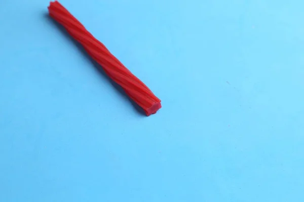 蓝色背景上的一块长长的红色扭曲的糖果 — 图库照片