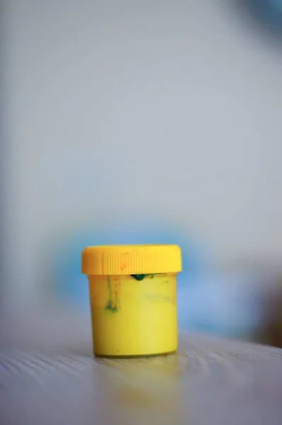 Tiro Foco Seletivo Vertical Pequeno Recipiente Tinta Amarela Uma Mesa — Fotografia de Stock