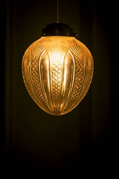 A vertical shot of a vintage lamp with a light on a dark background