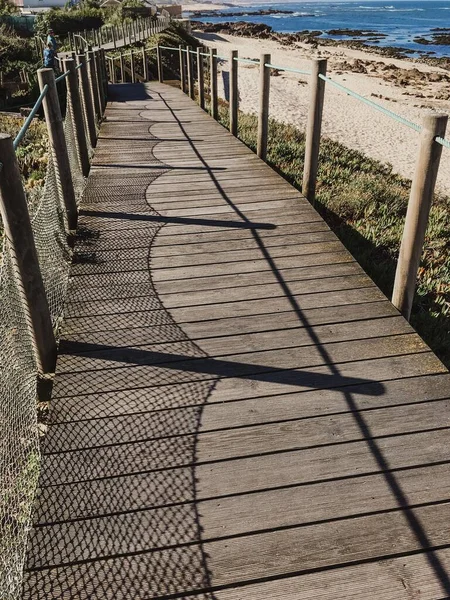 昼間の砂浜に囲まれた木道の垂直ショット — ストック写真