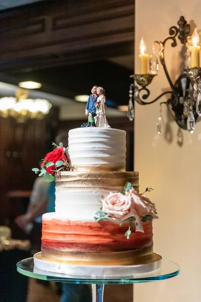 A vertical shot of a wedding cake on a tray in a restaurant with a blurry background