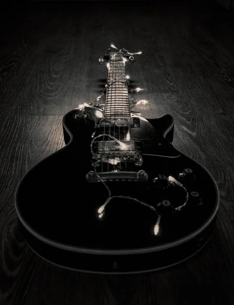 Eine Vertikale Graustufenaufnahme Einer Schwarzen Gitarre Mit Led Saitenbeleuchtung Auf — Stockfoto