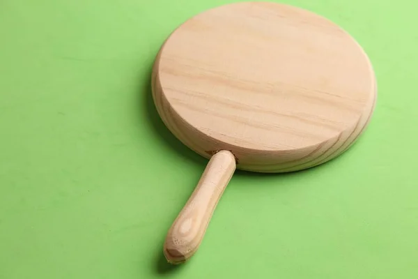 緑の背景にハンドル付きの木製の丸いピザボード — ストック写真