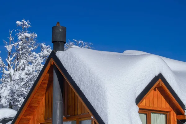 アルゼンチンのパタゴニアの青い空の下で雪に覆われた小さなコテージの屋根の閉鎖 — ストック写真