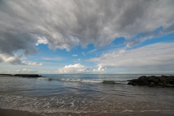 Een Strand Omringd Door Zee Kleine Rotsen Onder Een Blauwe — Stockfoto