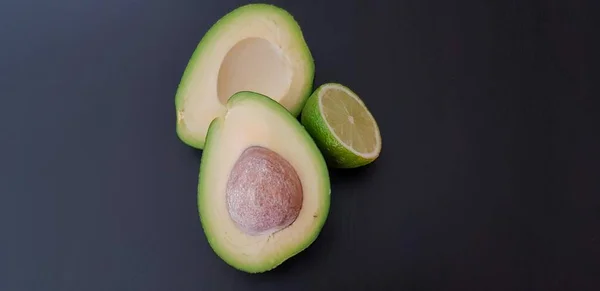 Avocado Limoen Helften Een Zwarte Achtergrond — Stockfoto