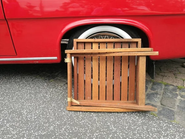 在街上一辆老式的红色轿车旁边的木制物体 — 图库照片
