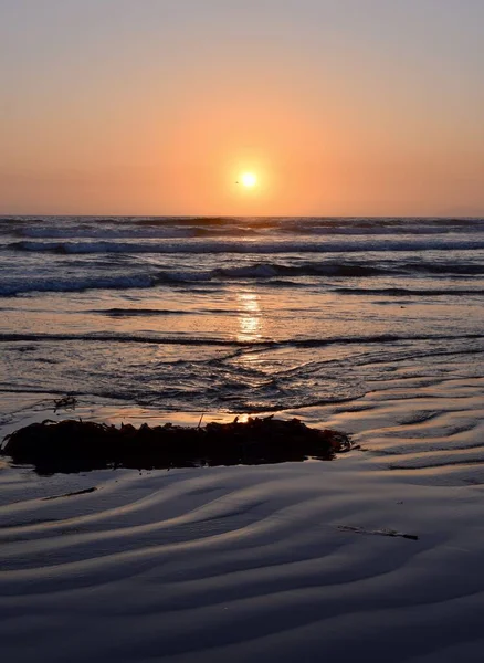 美しい夕日の中 海に囲まれたビーチの垂直ショット — ストック写真