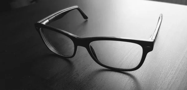 Schwarz Gerahmte Brille Auf Einem Beleuchteten Schwarzen Holzhintergrund — Stockfoto
