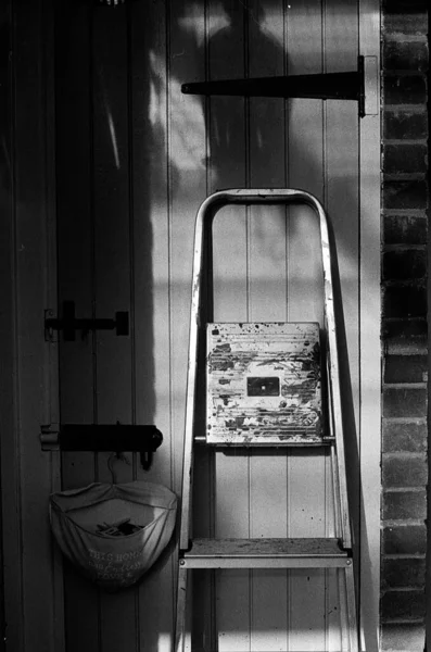 Eine Vertikale Graustufenaufnahme Einer Leiter Der Holztür Eines Backsteinhauses — Stockfoto