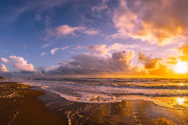 美しい夕日の間に曇った空の下で海に囲まれたビーチ 壁紙に最適 — ストック写真