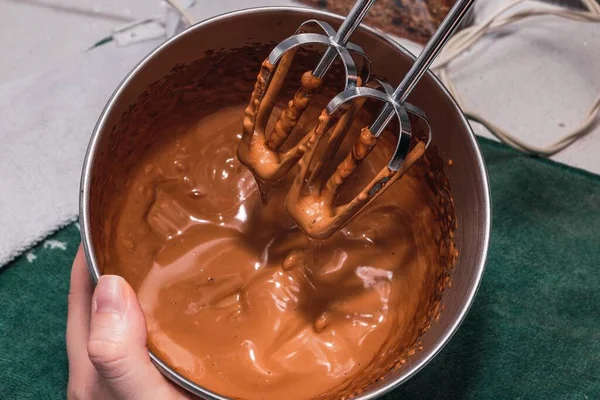 从一碗混合融化的巧克力烘焙概念中提炼出的手搅拌器金属搅拌器的顶部视图 — 图库照片