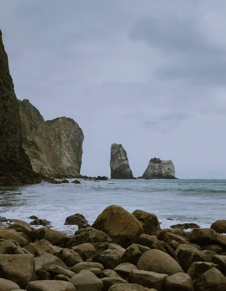 Bulutlu Bir Günde Kayalık Bir Plajın Kayalıklarla Çekilmiş Dikey Görüntüsü — Stok fotoğraf