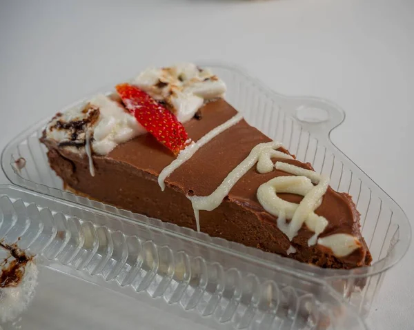 プラスチック製の箱の中にクリーム入りチョコレートケーキの高角度ショット — ストック写真