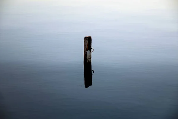 穏やかな日に一人で海に立っている古い金属製の係留ポール — ストック写真