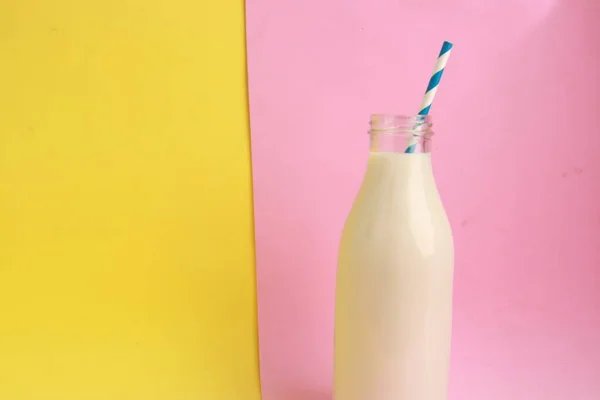 Крупный План Бутылки Молока Соломой Изолированной Розовом Желтом Фоне — стоковое фото