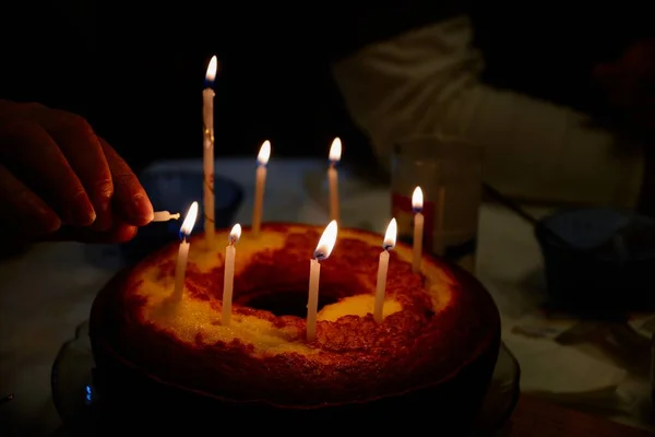 背景のぼんやりとした背景にろうそくを燃やす誕生日ケーキの浅いフォーカスショット — ストック写真