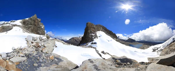 太陽の光の下で高雪と氷に覆われた山脈のパノラマのショット — ストック写真