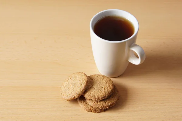 木製の表面にコーヒーカップとおいしいクッキーのクローズアップショット — ストック写真