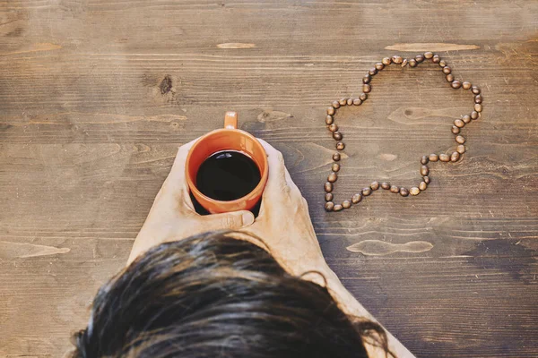 Nad Głową Ujęcie Osoby Trzymającej Filiżankę Kawy Paloną Fasolą Stole — Zdjęcie stockowe
