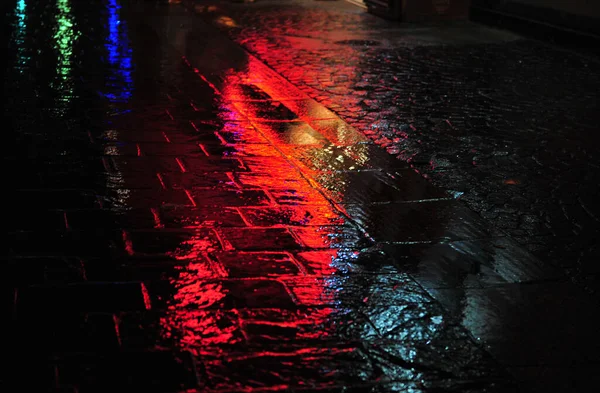 Крупный План Отражений Неоновых Огней Мокрой Дождливой Улице Булыжника Ночью — стоковое фото