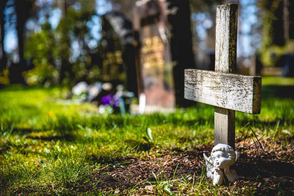 墓地里一个木制十字架和一个小天使雕塑的特写镜头 — 图库照片