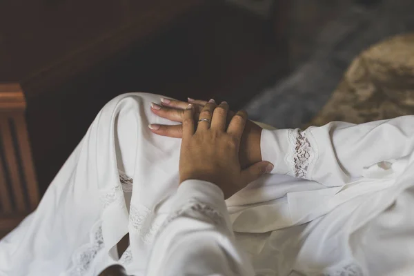 一个穿着白色婚纱 双手放在膝盖上的坐在那里的女性的特写镜头 — 图库照片