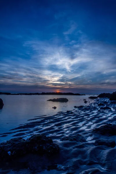 美しい夕日の間に砂浜の石の垂直ショット — ストック写真