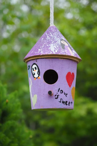 上面写着 爱情是甜蜜的 的紫色木材鸟舍 — 图库照片