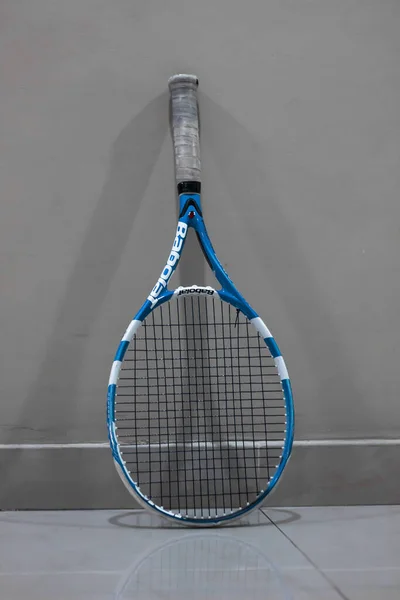 Gri Duvara Dayalı Bir Tenis Raketinin Dikey Çekimi — Stok fotoğraf