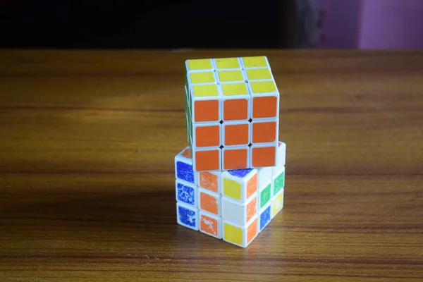 在背景模糊的桌子上的未解决立方体上的已解决Rubik立方体的高角视图 — 图库照片